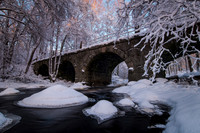 Winter creek under old forest bridge