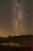 Milky Way above pond in summer with light mist