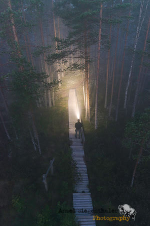 Person on path with headlamp in dawn fog