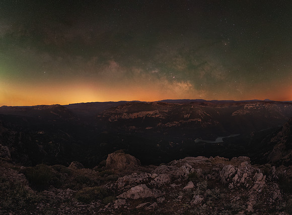 Milky Way core rising horizontally on horizon from mountain edge and above a grand valley